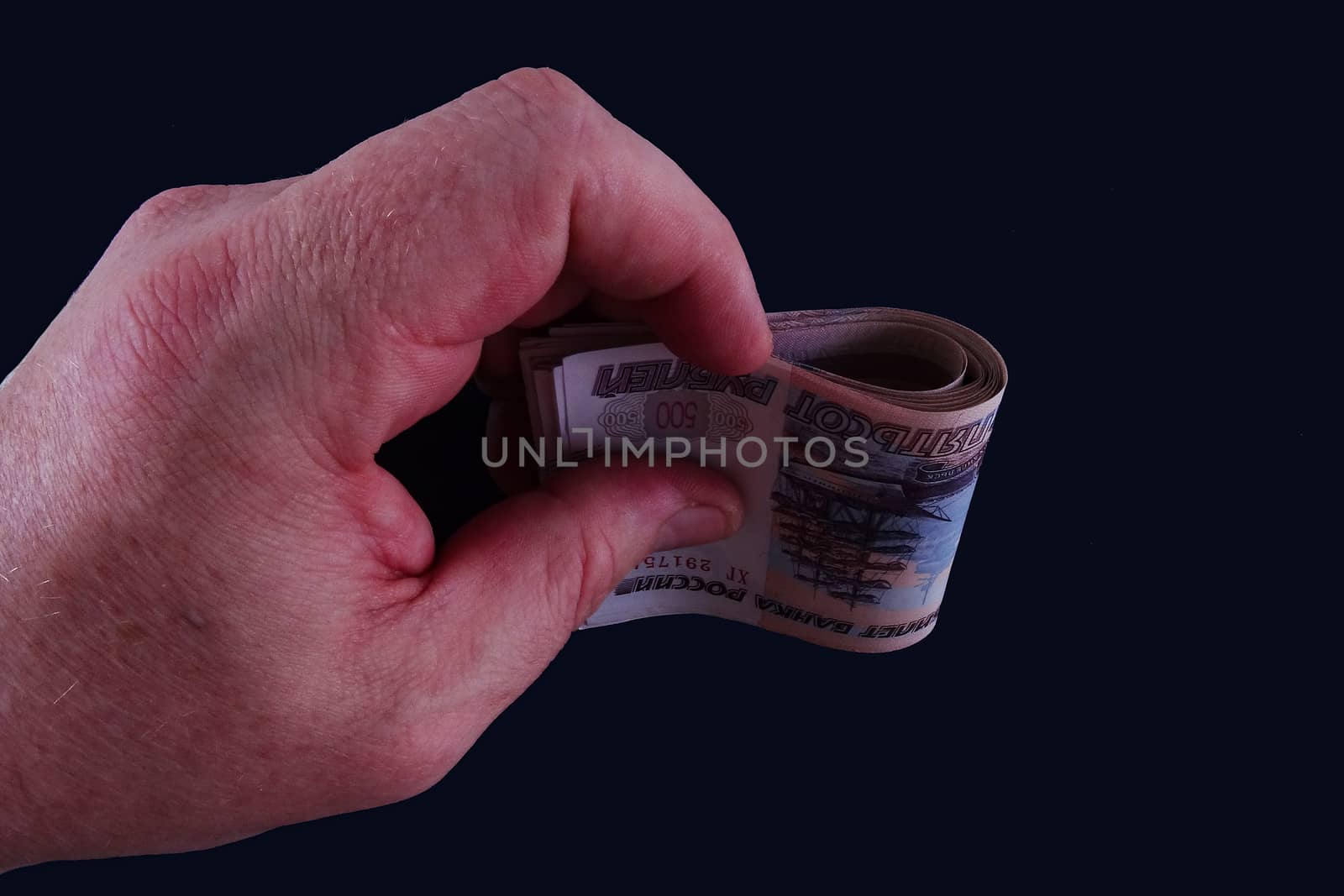 In the hand of the banknote on dark background
