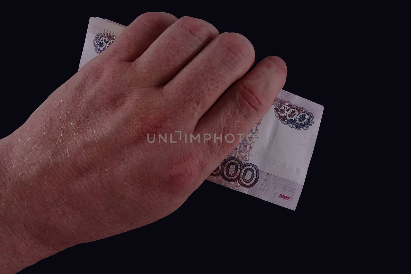 In the hand of the banknote on dark background