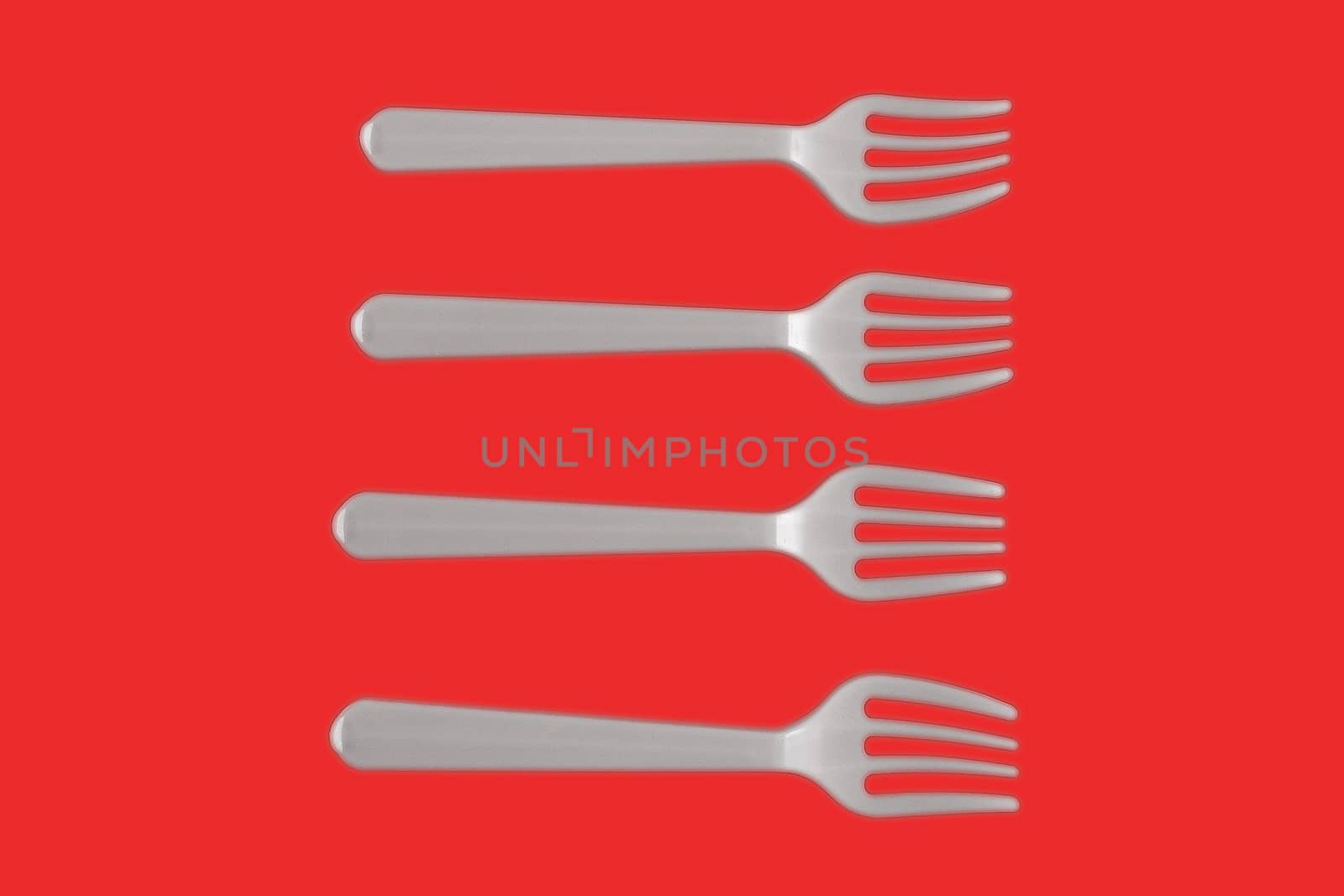 four plastic white forks on a red background