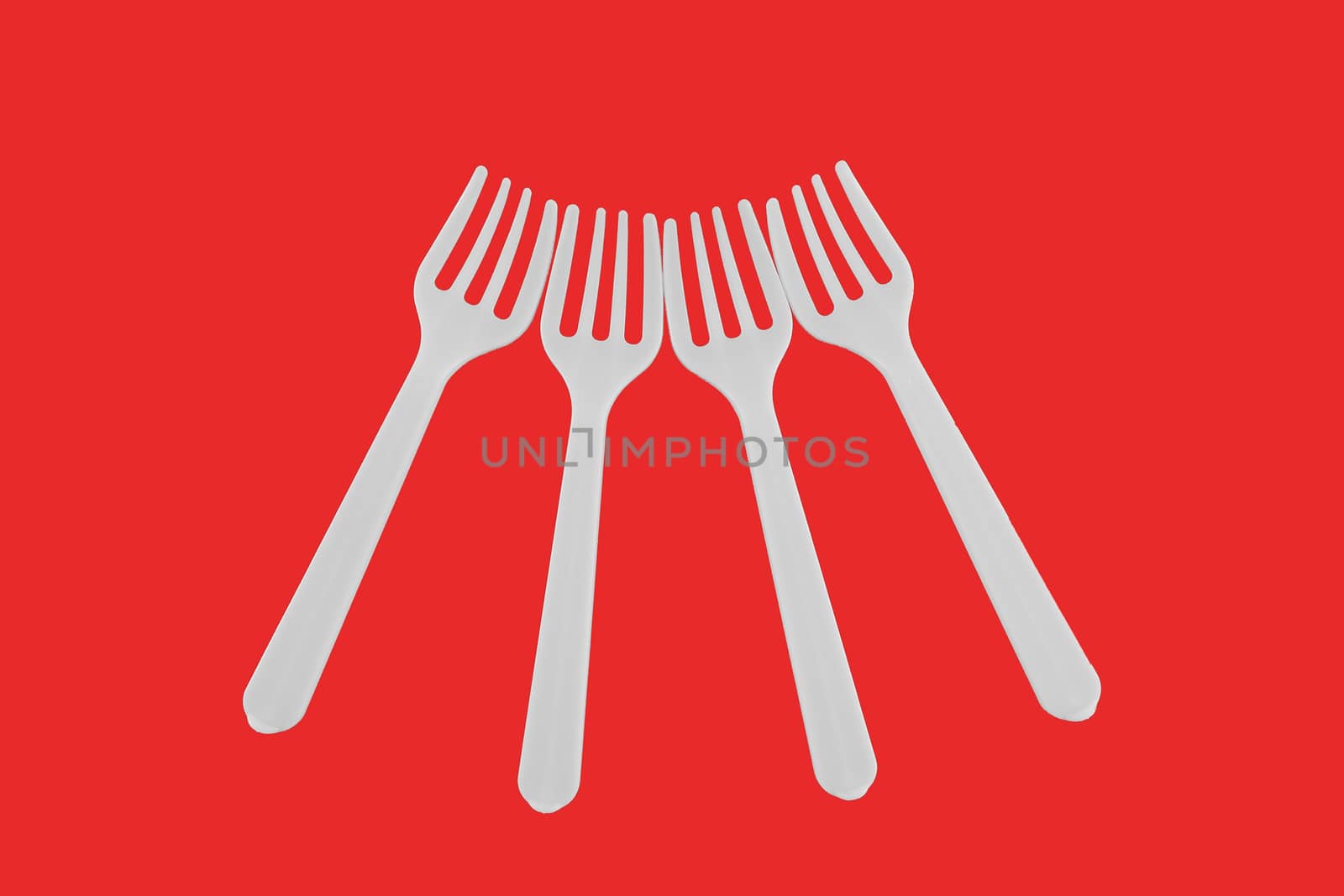 four plastic white forks on a red background