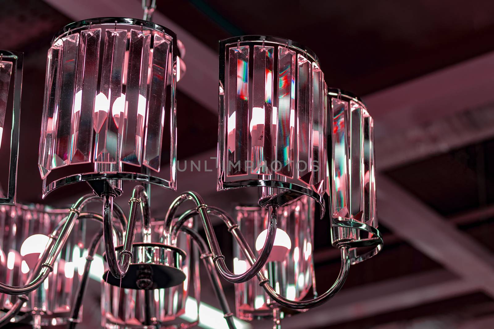 Fragment of a pink glass chandelier against the ceiling.