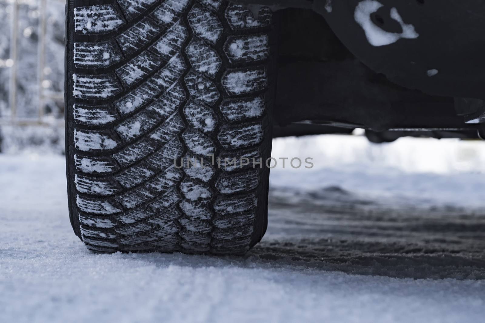 The wheel of the car is coated in winter tires in the snow.