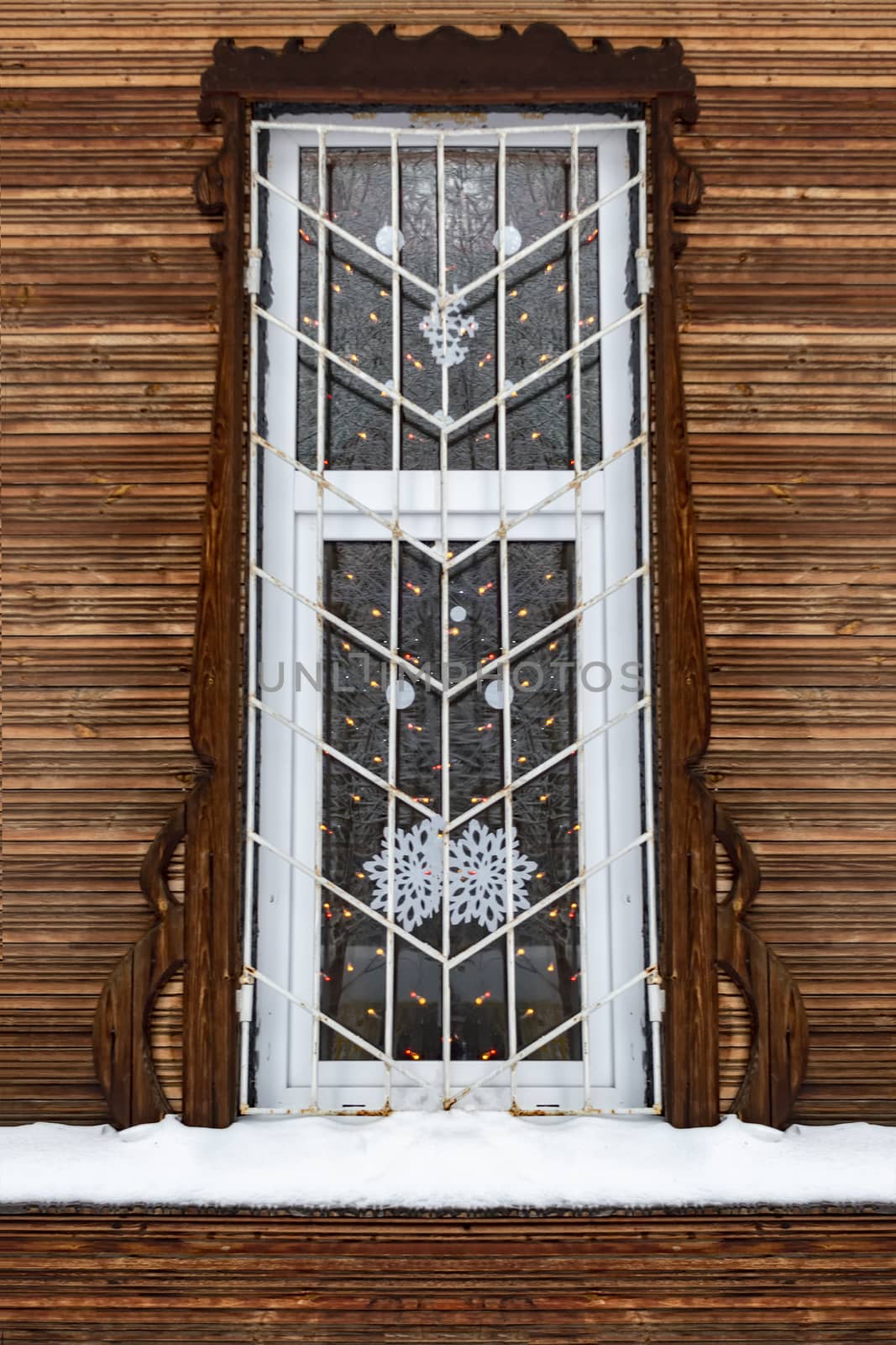 A barred window in an old wooden house. Winter.