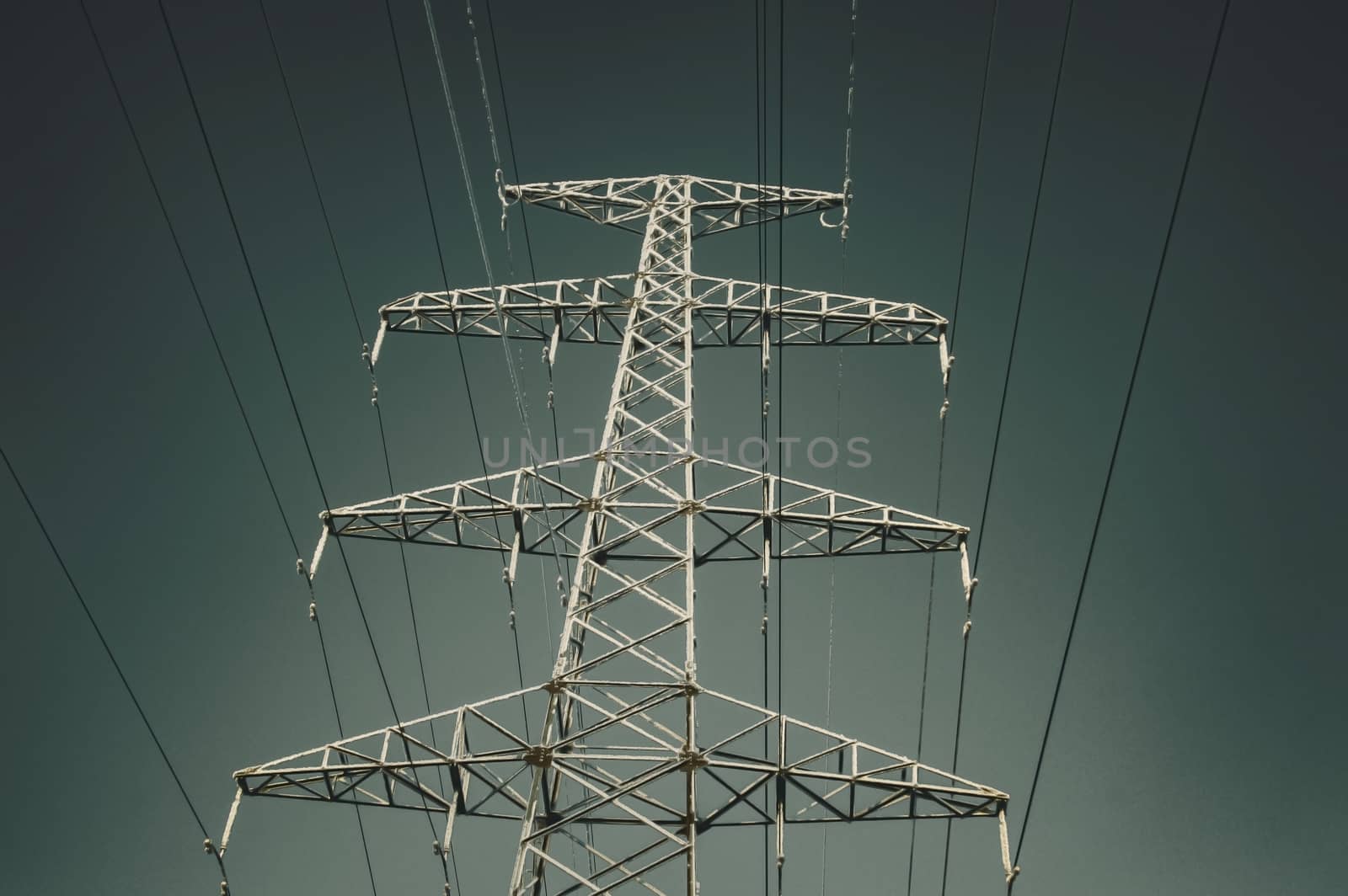 The support of the high voltage line in winter. View from below. Gradient sky. Vertical image.