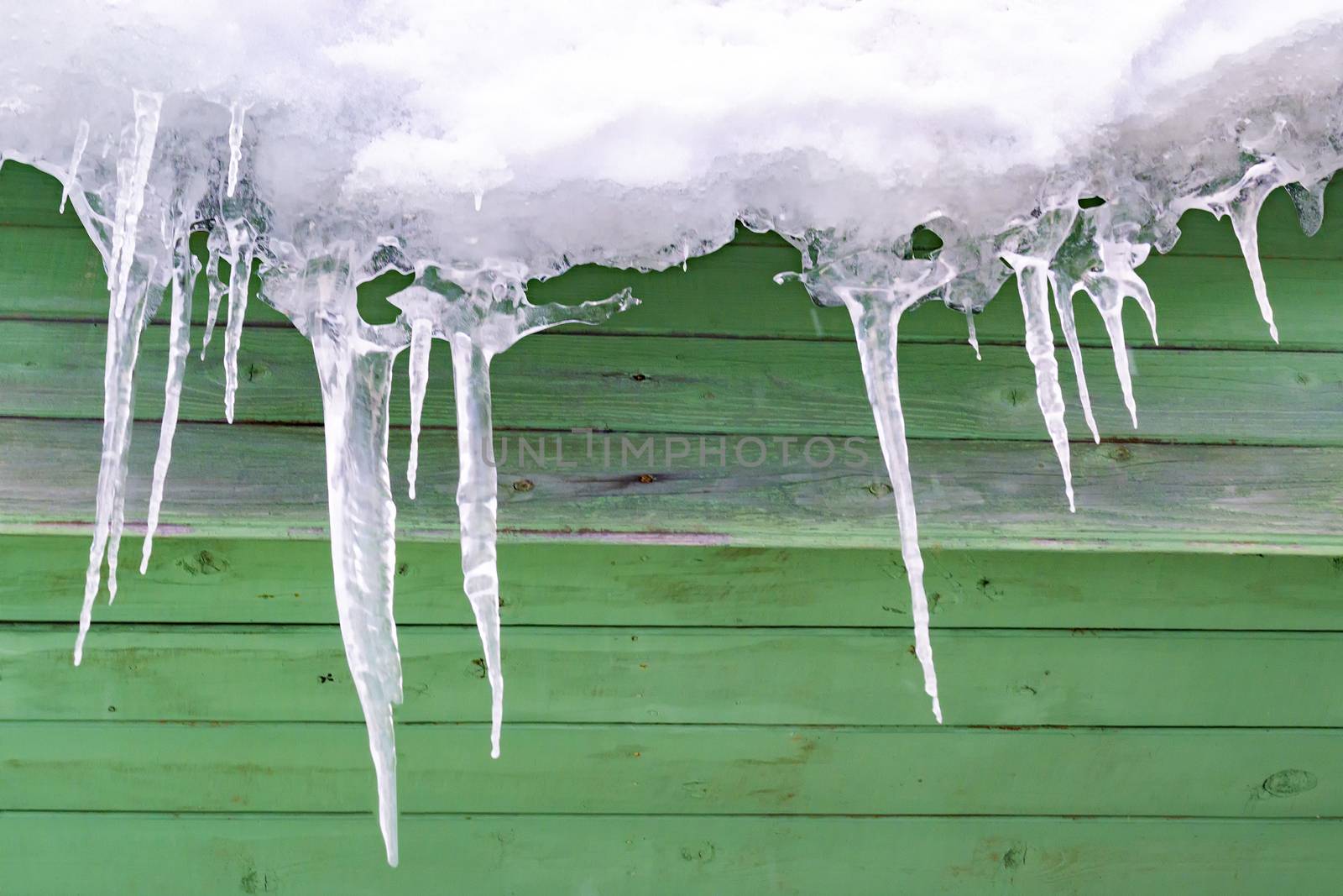 Icicles are icy against backdrop of old wooden wall.
