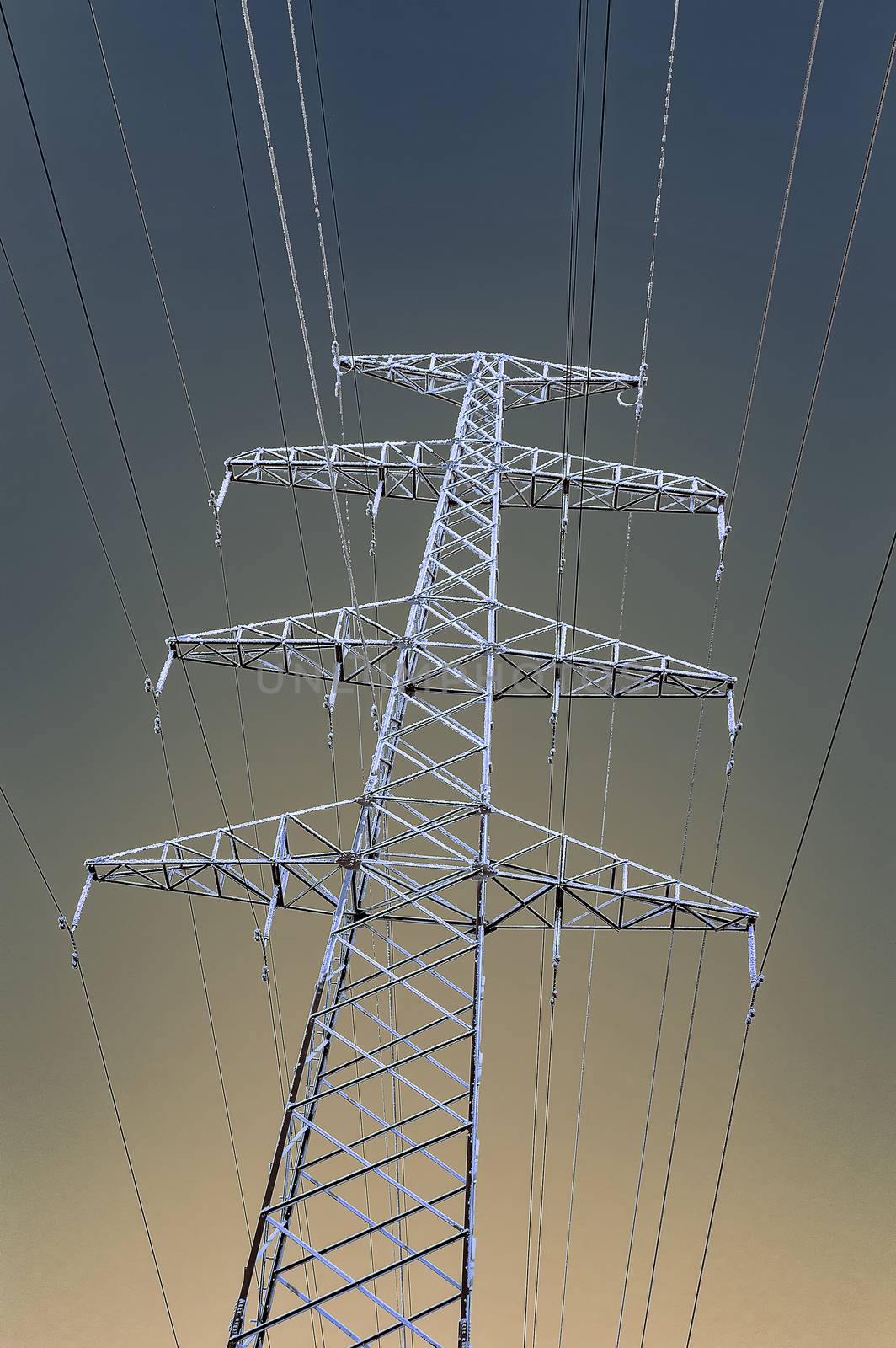The support of the high voltage line in winter. View from below. Gradient sky. Vertical image.