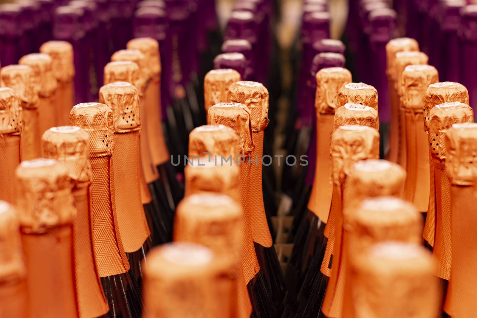 Champagne bottles tops arranged in store shelf. Front view.