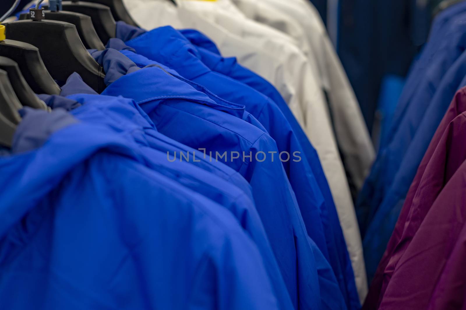 Several rows with top clothes on hangers.