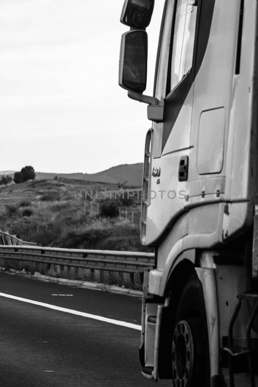 Black and white photo, concept of motion, loaded European truck in motion on asphalt road, transportation and delivery concept. Bucharest, Romania, 2020