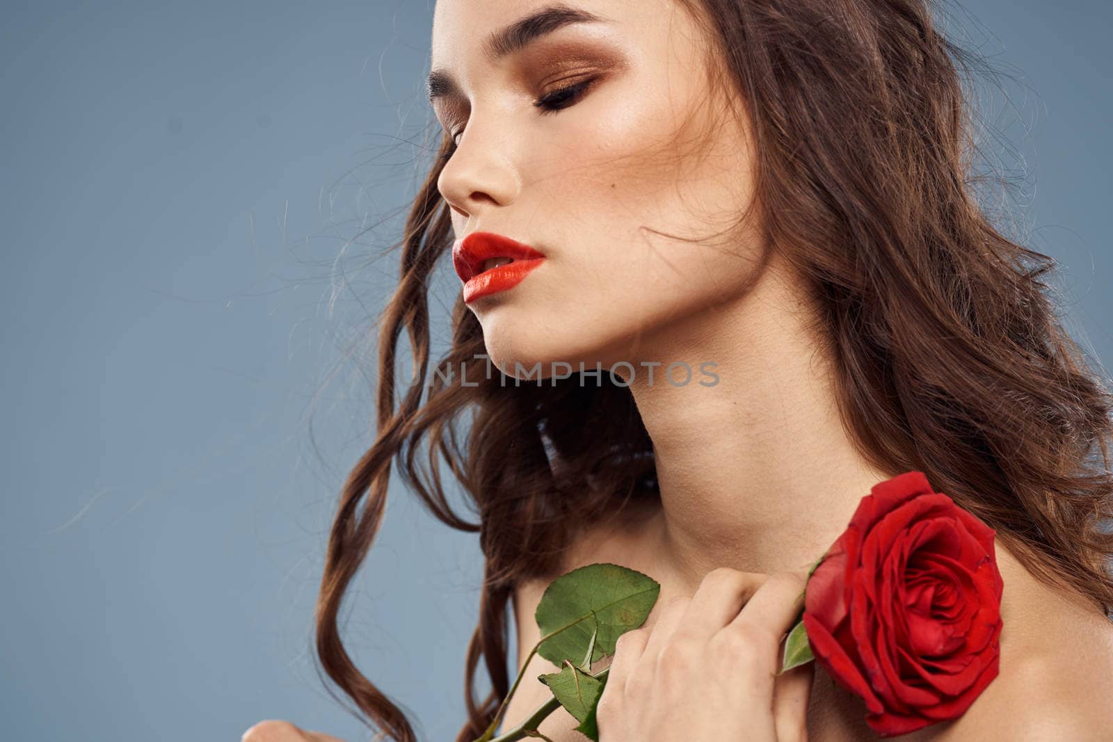 Woman portrait with red rose near the face on gray background and makeup curly hair by SHOTPRIME