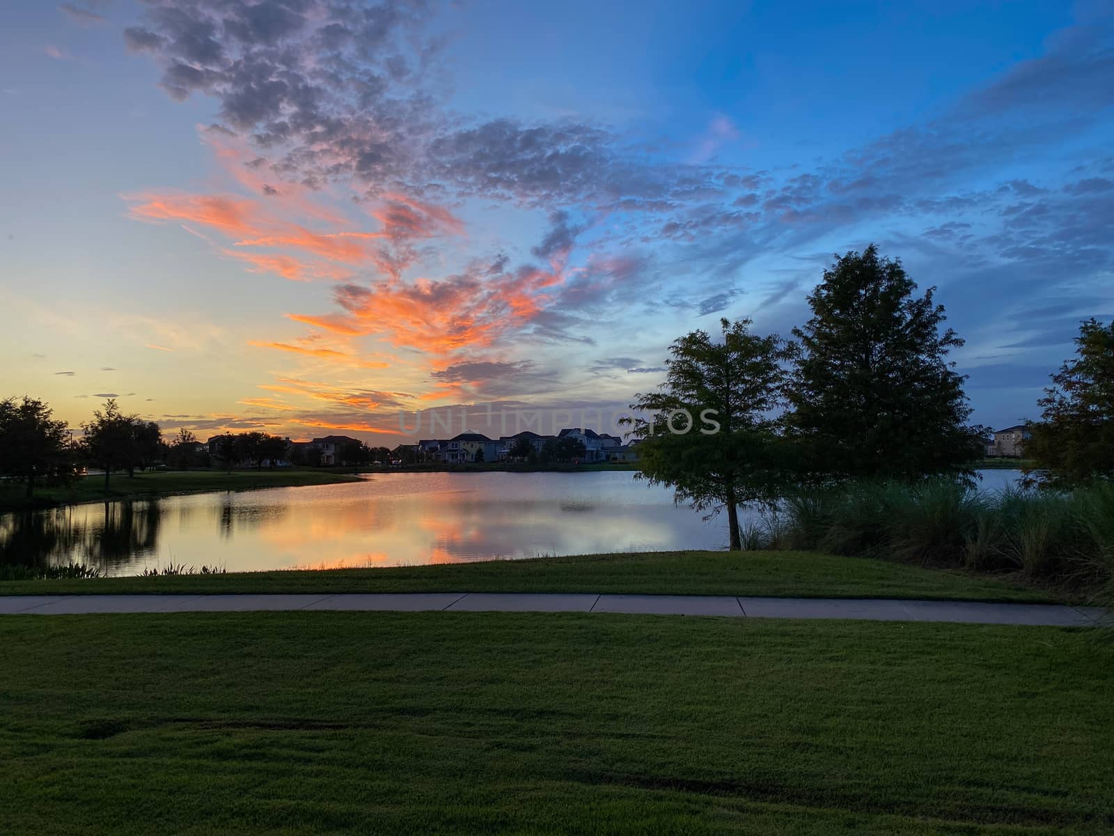 A colorful sunset over a lake in a neighborhood by Jshanebutt