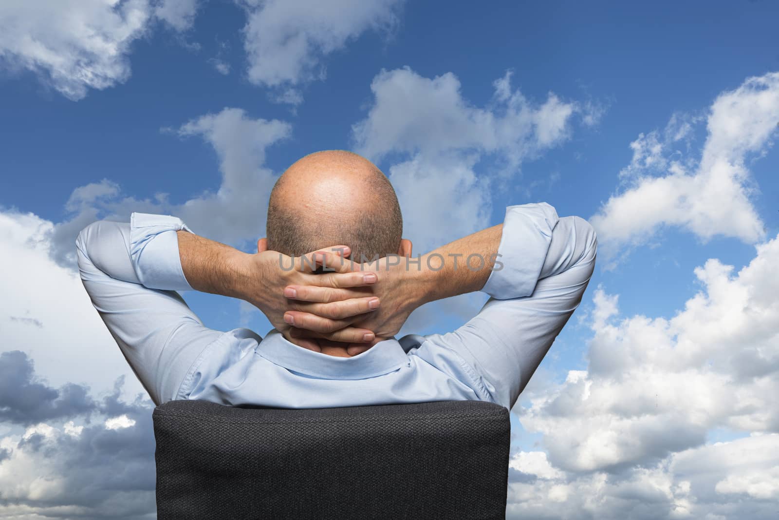 a relaxed man shot from behind in front of a cloudy sky