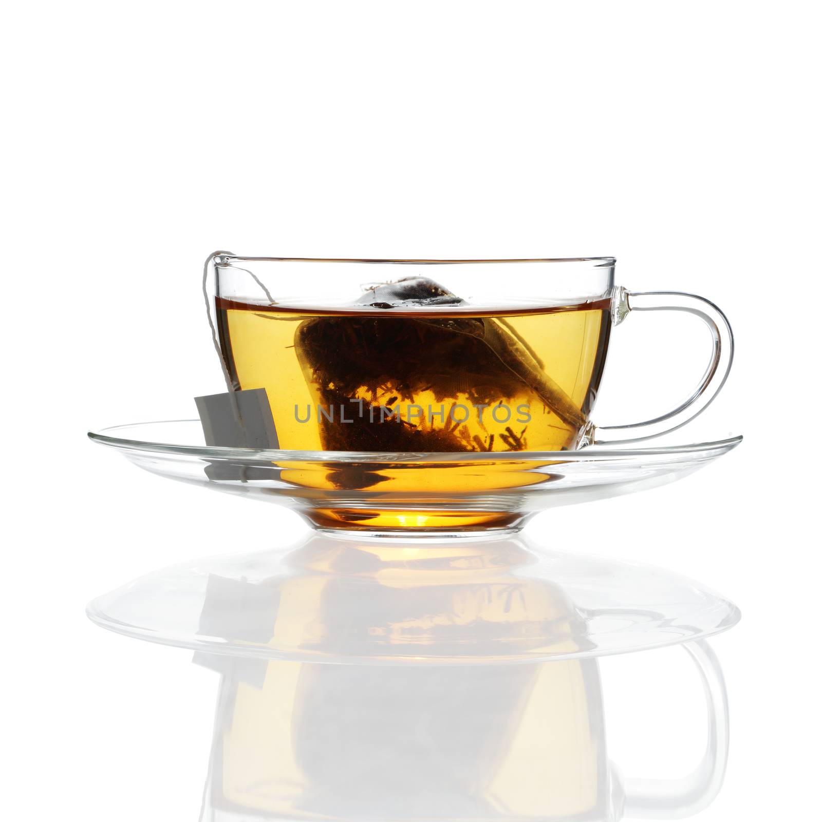 Tea in glass cup with saucer on white background with reflection