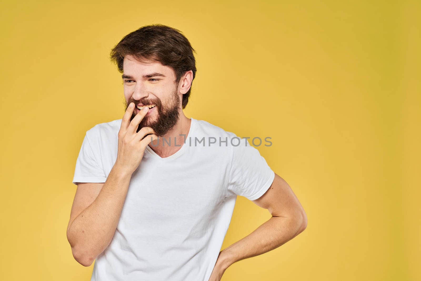 Bearded man white t-shirt emotions gestures with hands fun yellow background. High quality photo