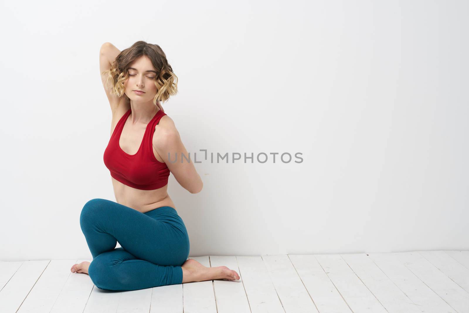 woman doing yoga full length indoors blue leggings red tank top. High quality photo