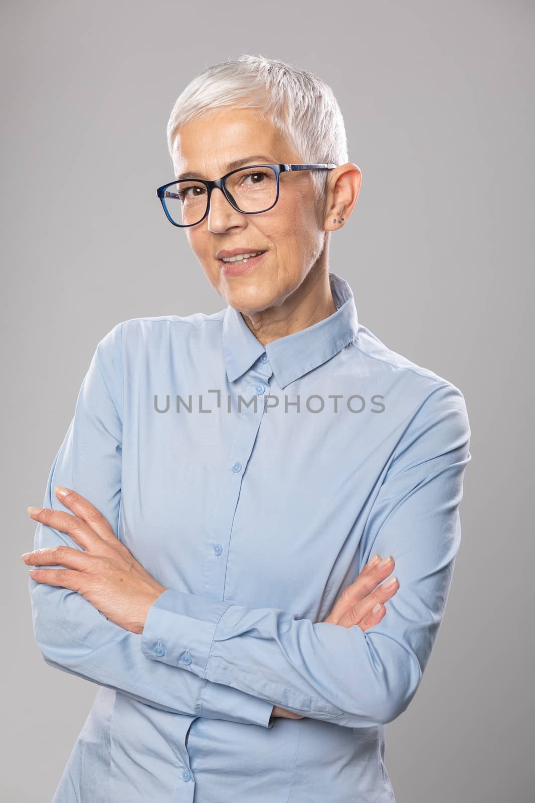 Senior businesswoman with glasses in a blue shirt and short whit by adamr