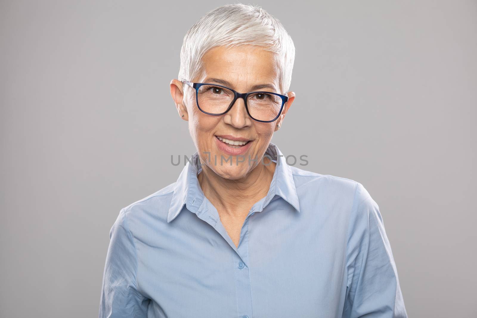 Smart senior businesswoman with glasses in a blue shirt and gray by adamr