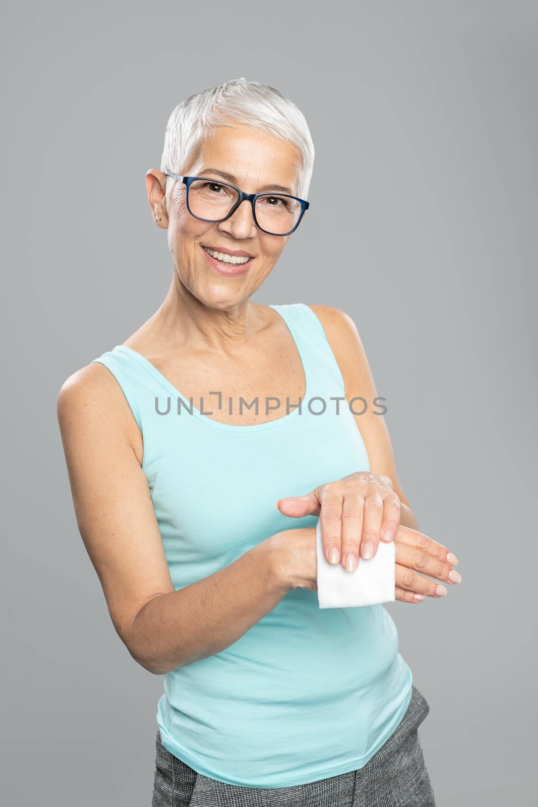 Senior woman cleaning hands with wet wipes - care for health and by adamr