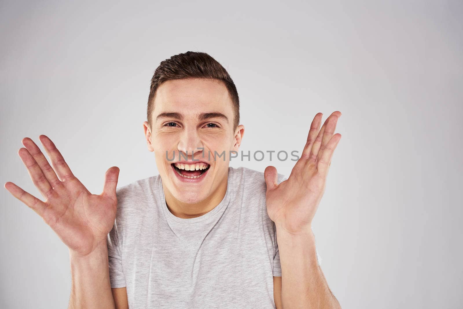 Man in a white t-shirt emotions gestures with hands close-up cropped view light background by SHOTPRIME