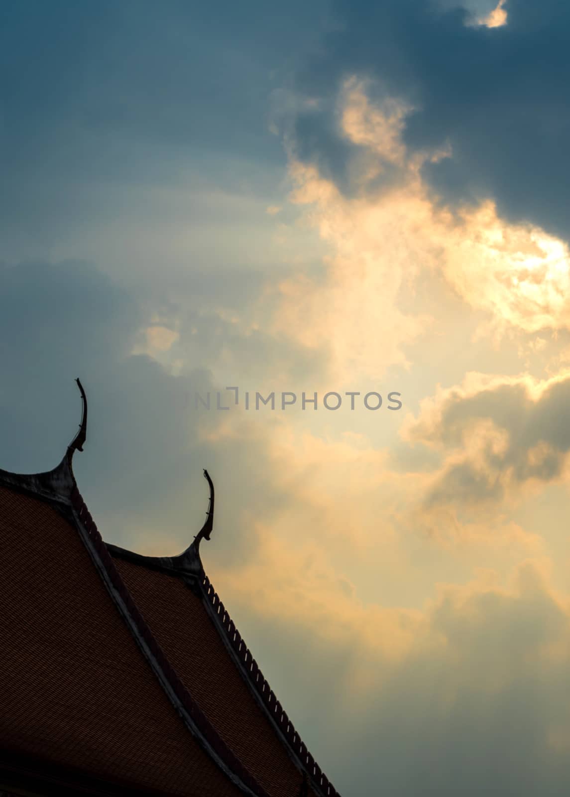 Sun beam behind the sunset clouds over the buddhist temple