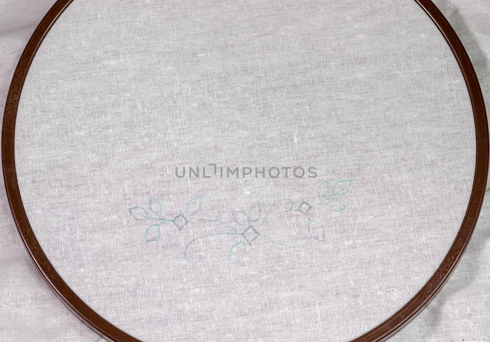 Wooden Embroidery hoop with a clean white piece of linen cloth and a simple design.