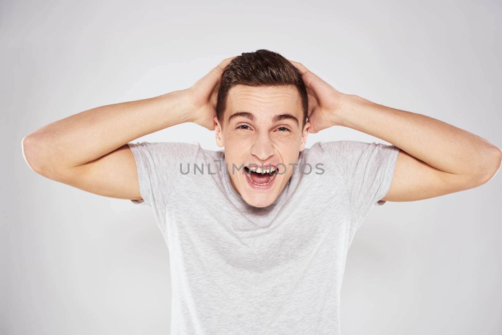 Man in a white t-shirt emotions gestures with hands close-up cropped view light background. High quality photo