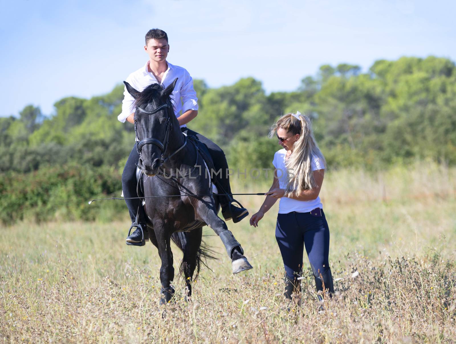  riding teenager are training her black horse with teacher