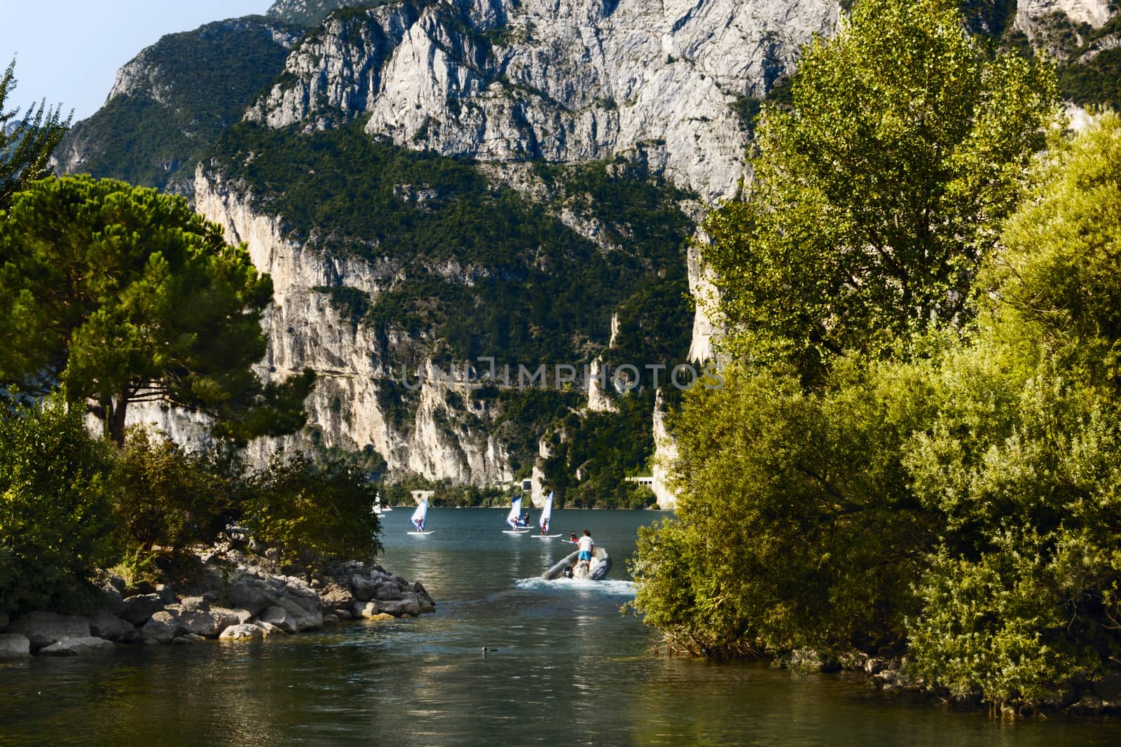 Foreshortening  on the lake Garda in the North of Italy ,it's a sunny day ,everybody's surfing ,in the background cliffs fall sheer into the lake ,