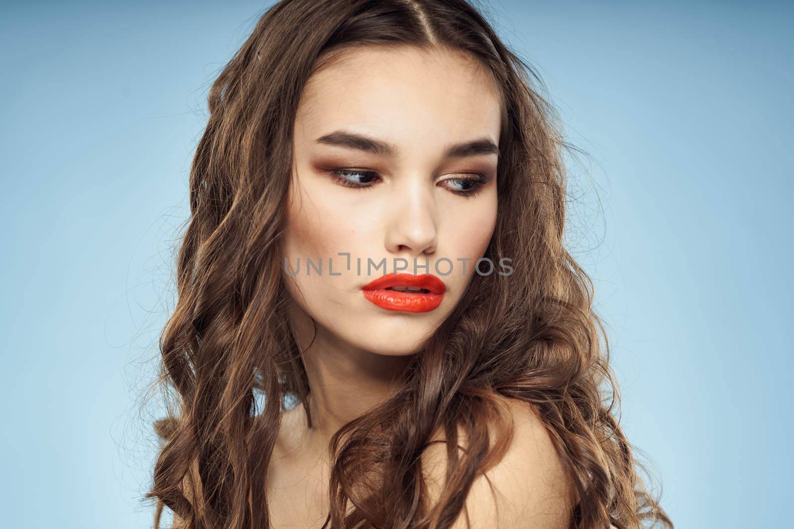 Elegant brunette fashionable hairstyle bright makeup naked shoulders close-up blue background. High quality photo