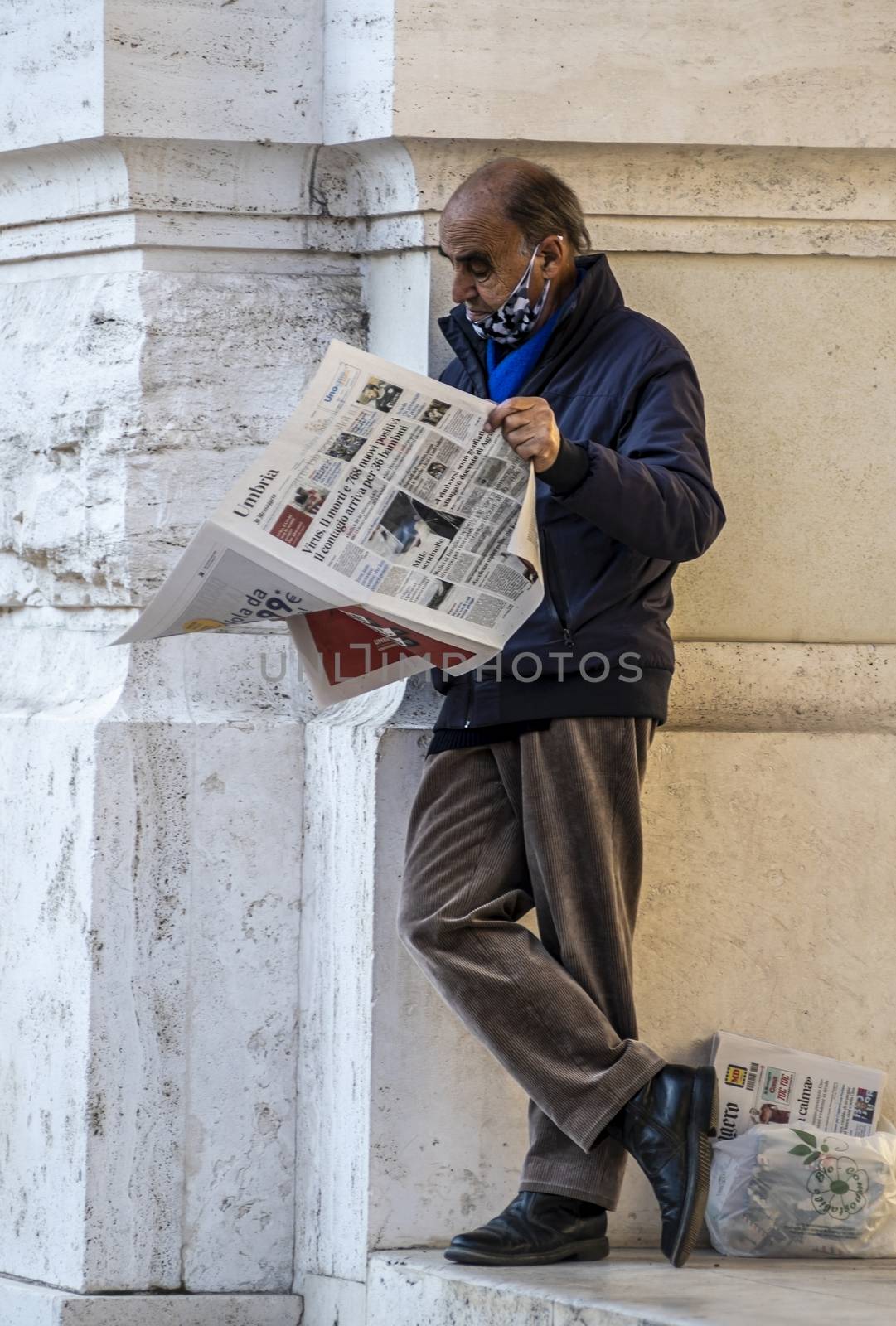 man leaning against a building reading the newspaper by carfedeph