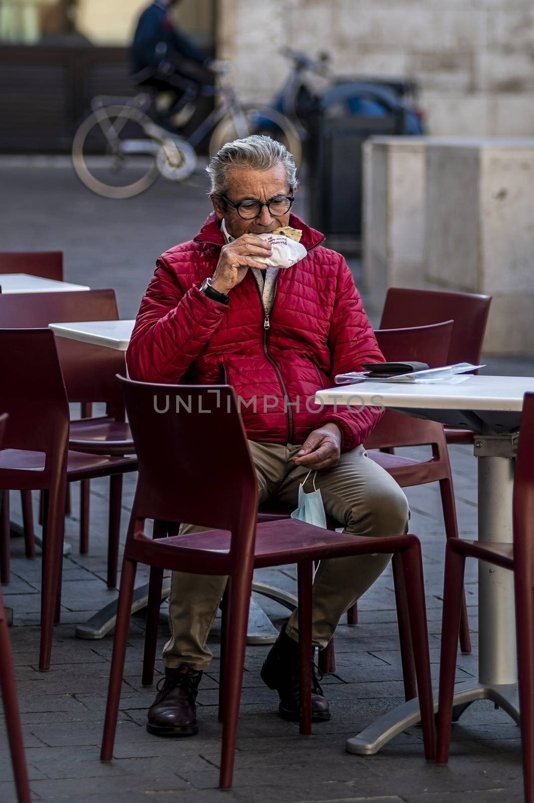 man sitting at a table eats a piece of pizza by carfedeph