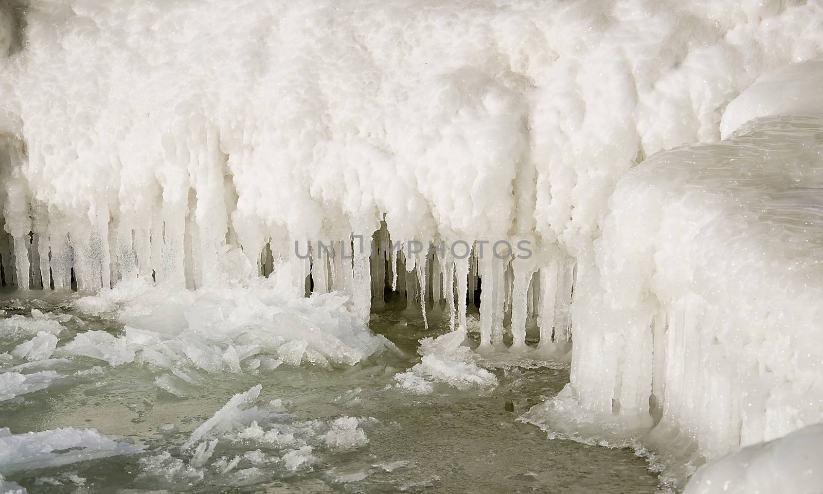 Icicles in a frozen ice wall. Climate Change. Piece of ice against the background of the glacier wall. Winter creek.