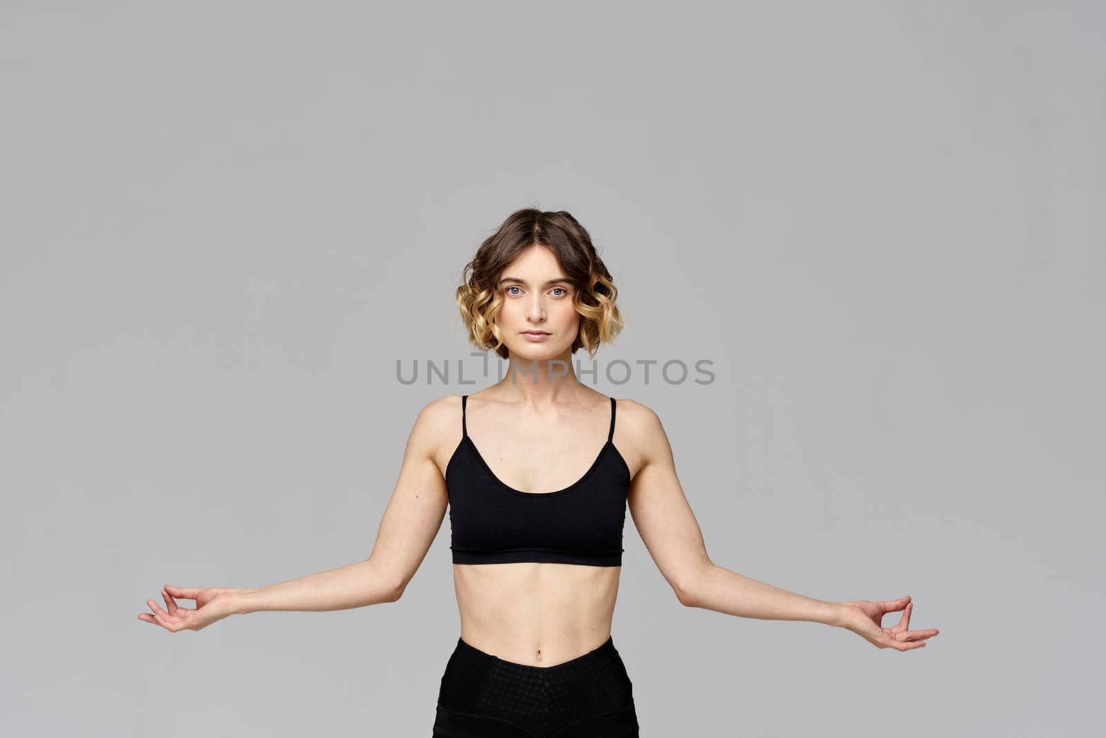 A slender woman is gesturing with her hands on a gray background Sport Fitness figure. High quality photo