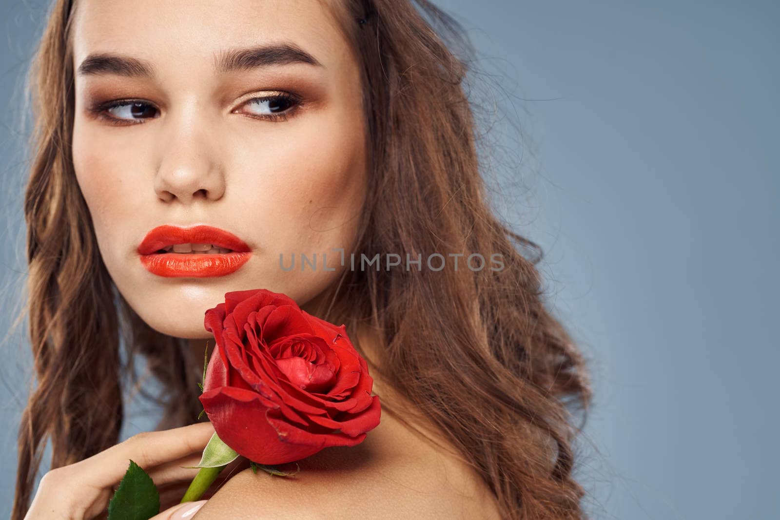 woman with a rose in her hands naked shoulders evening makeup red lips. High quality photo