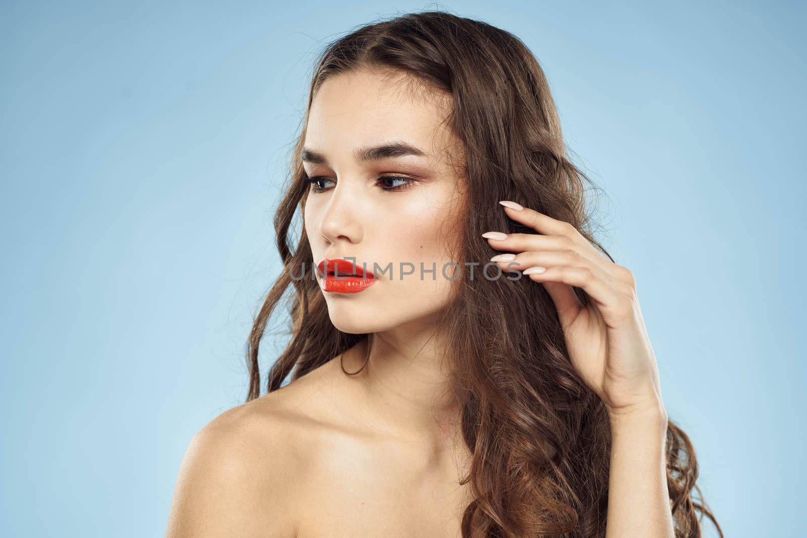 Brunette naked shoulders red lips fashionable hairstyle blue background. High quality photo