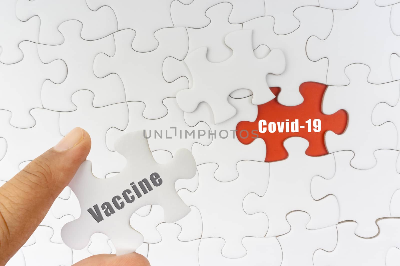 Hand holding jigsaw puzzle with text VACCINE and COVID-19 by silverwings