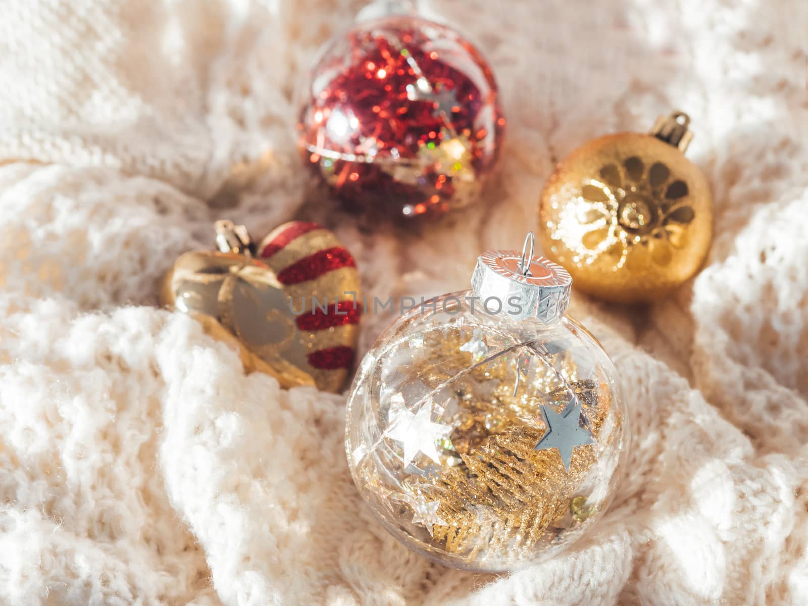Decorative balls for Christmas tree on cable-knit sweater. Transparent sphere with red, golden spangles inside. Winter holiday spirit. New year celebration.