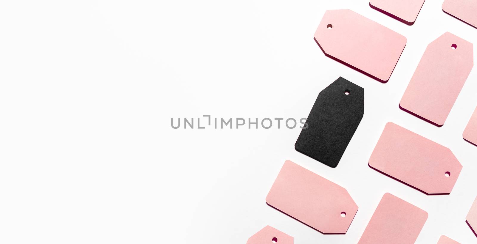 Top view on pattern of many pink and one black clothes tags on white background. Glamorous labels with copy space. Symbol of black Friday sale and shopping. Flat lay.