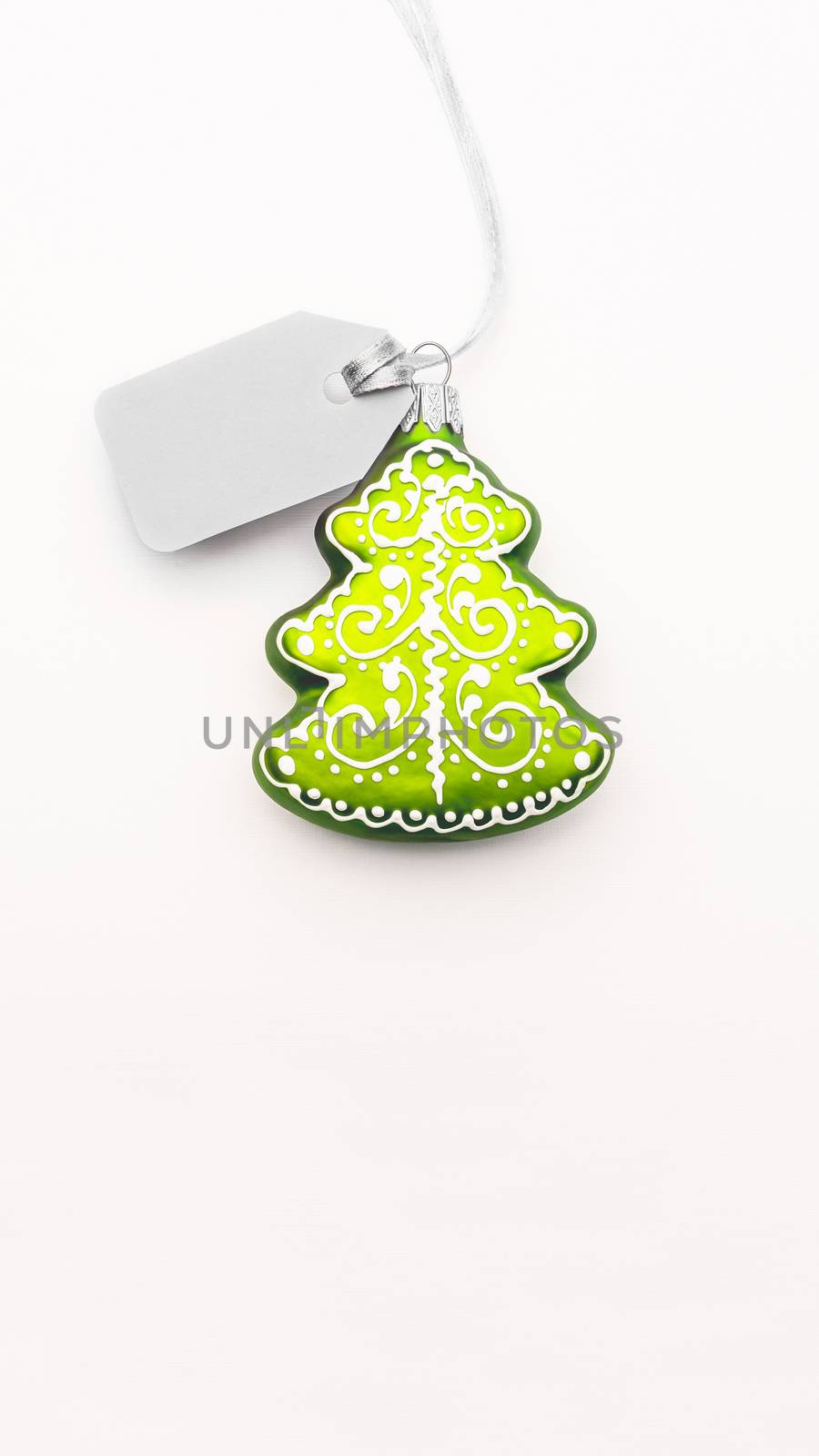 Decorative Christmas tree with grey price tag on white background. Clear label on silver thread. New Year symbol of sale and shopping. Top view, flat lay.