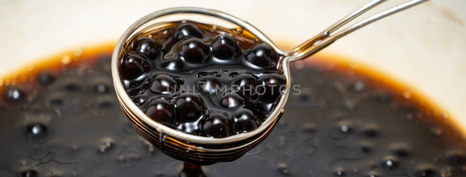 Cooking, boiling brown sugar flavored tapioca pearl balls, ingredient of bubble tea, preparing food and drink, close up, recipe cookbook steps design concept.