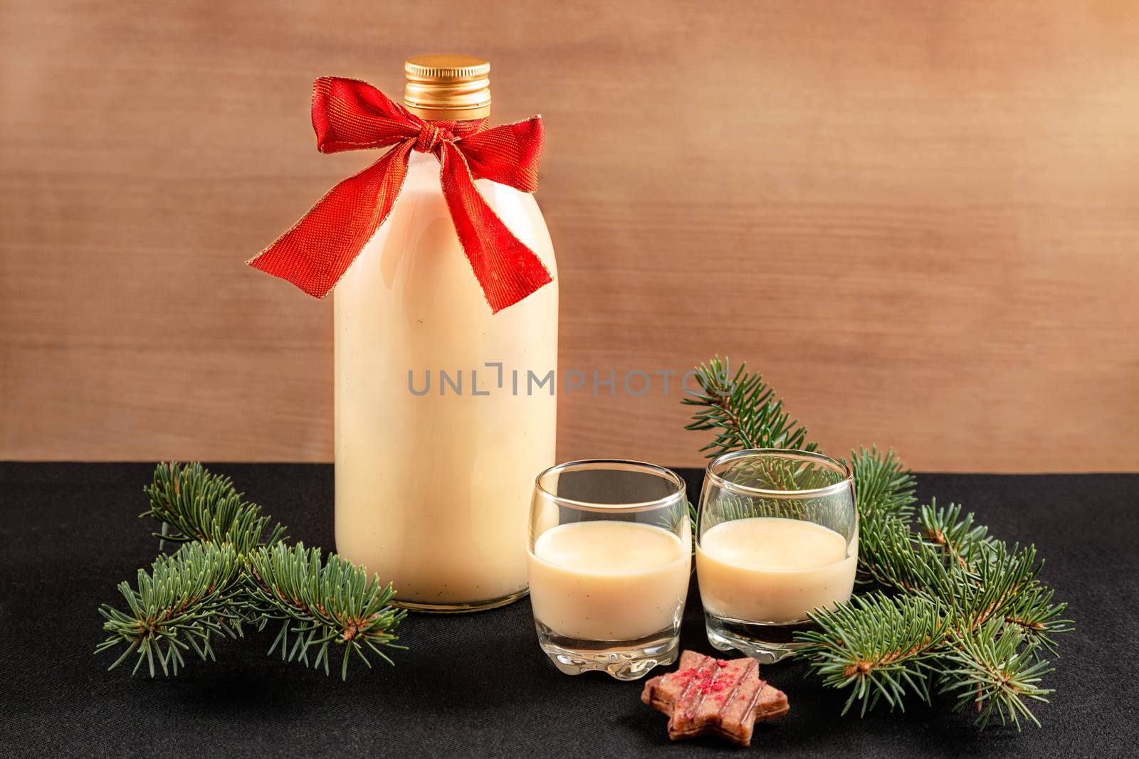 Homemade eggnog in bottle and two glasses with Christmas decoration on wooden background