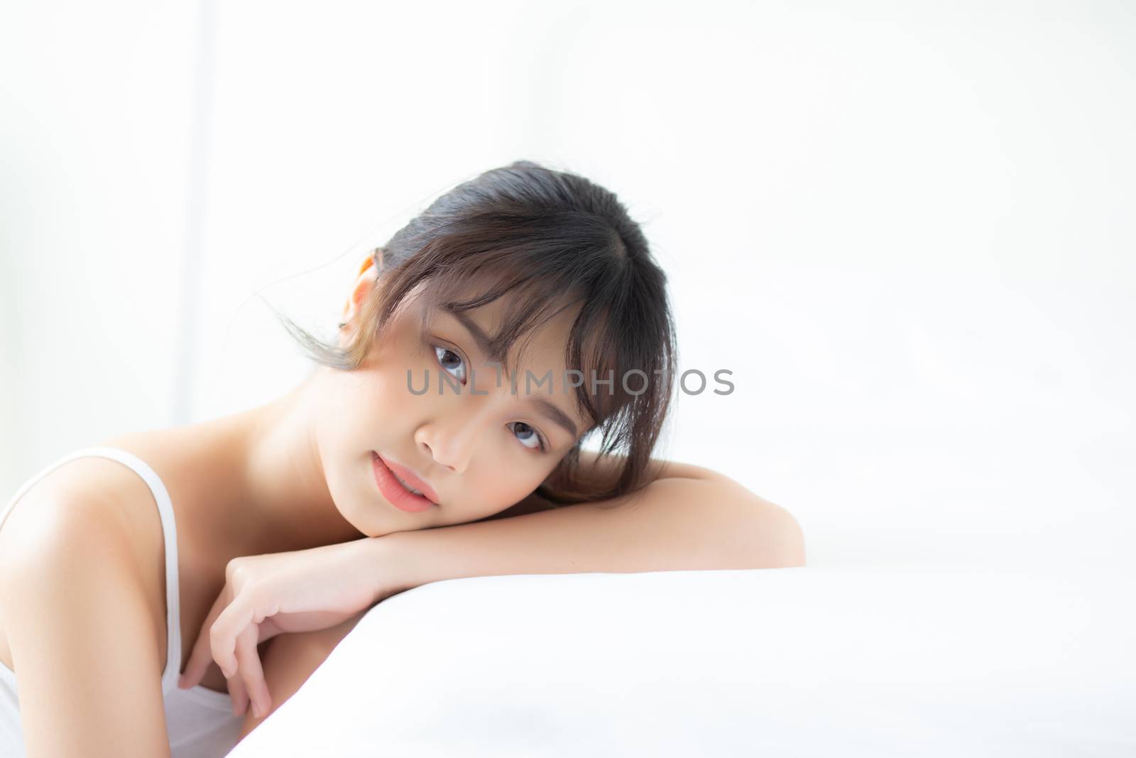 Lifestyle beautiful portrait young asian woman relax lying sleep and smile while wake up with sunrise at morning, girl with happy and fun in the bedroom, health and wellness concept.