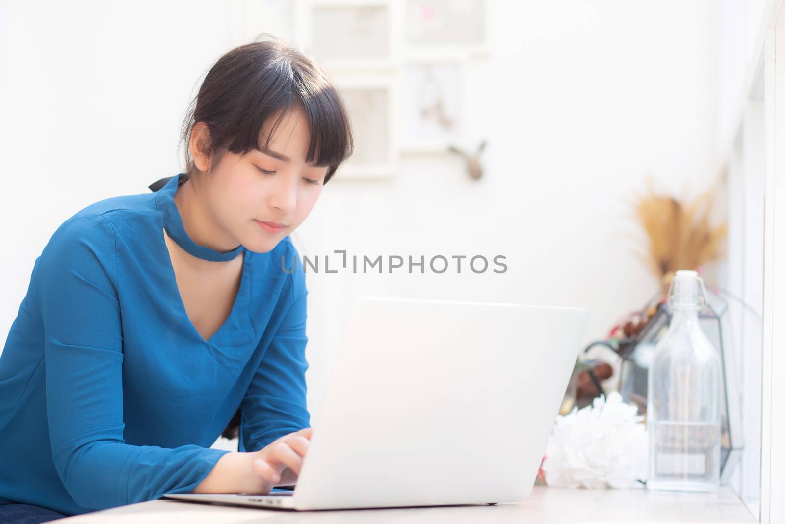 Beautiful portrait asia young woman working online on laptop sitting at cafe shop, professional female freelance using notebook computer, business and communication concept.