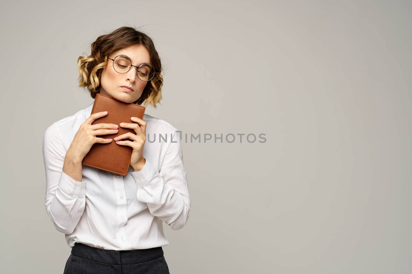 Business woman with notepad and glasses on a light background hairstyle success emotions. High quality photo