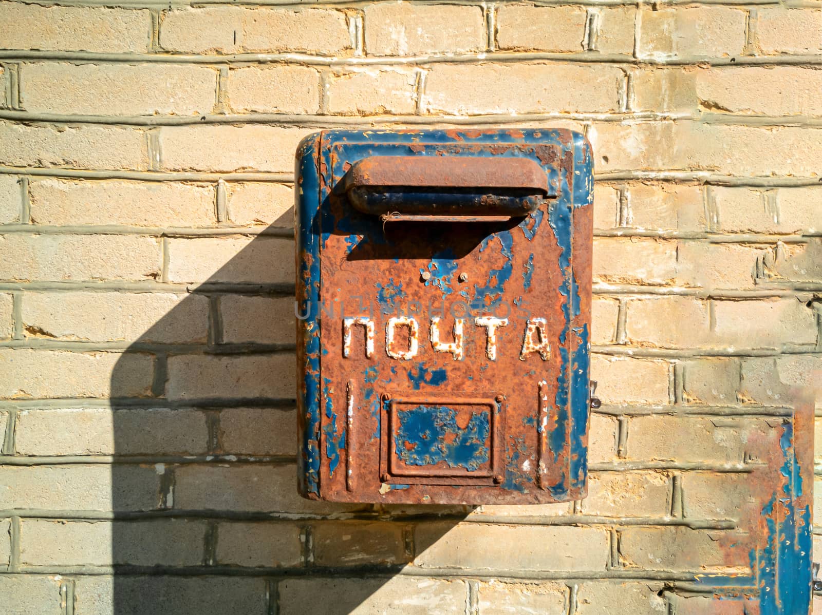 Old letterbox of Soviet era on the wall. Old post box. metal box for mail hanging on dirty wall.