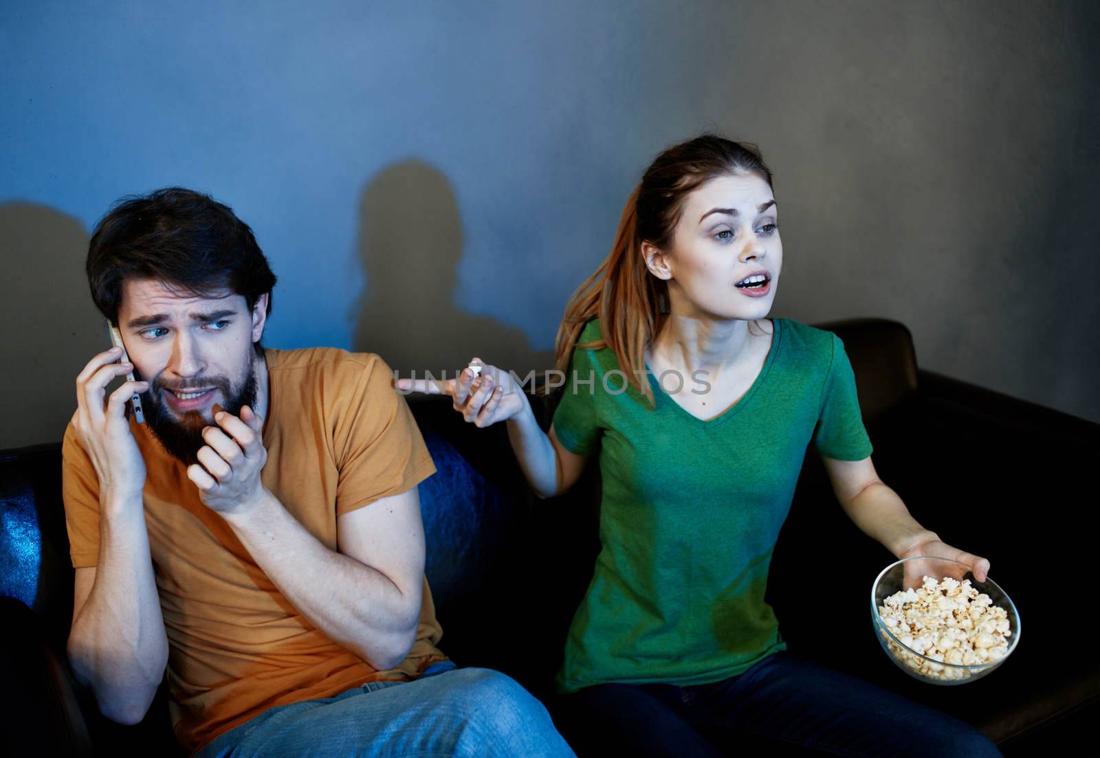 Men and women on the couch In a dark room watching a horror movie. High quality photo