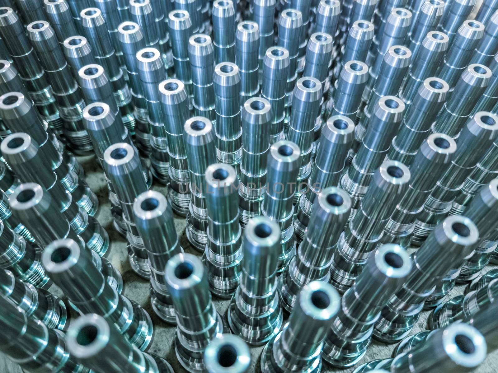 Shiny long steel parts full frame background, clean steel threaded rods after fine cnc turning. Standing vertically in a rows with selective focus in diagonal composition.