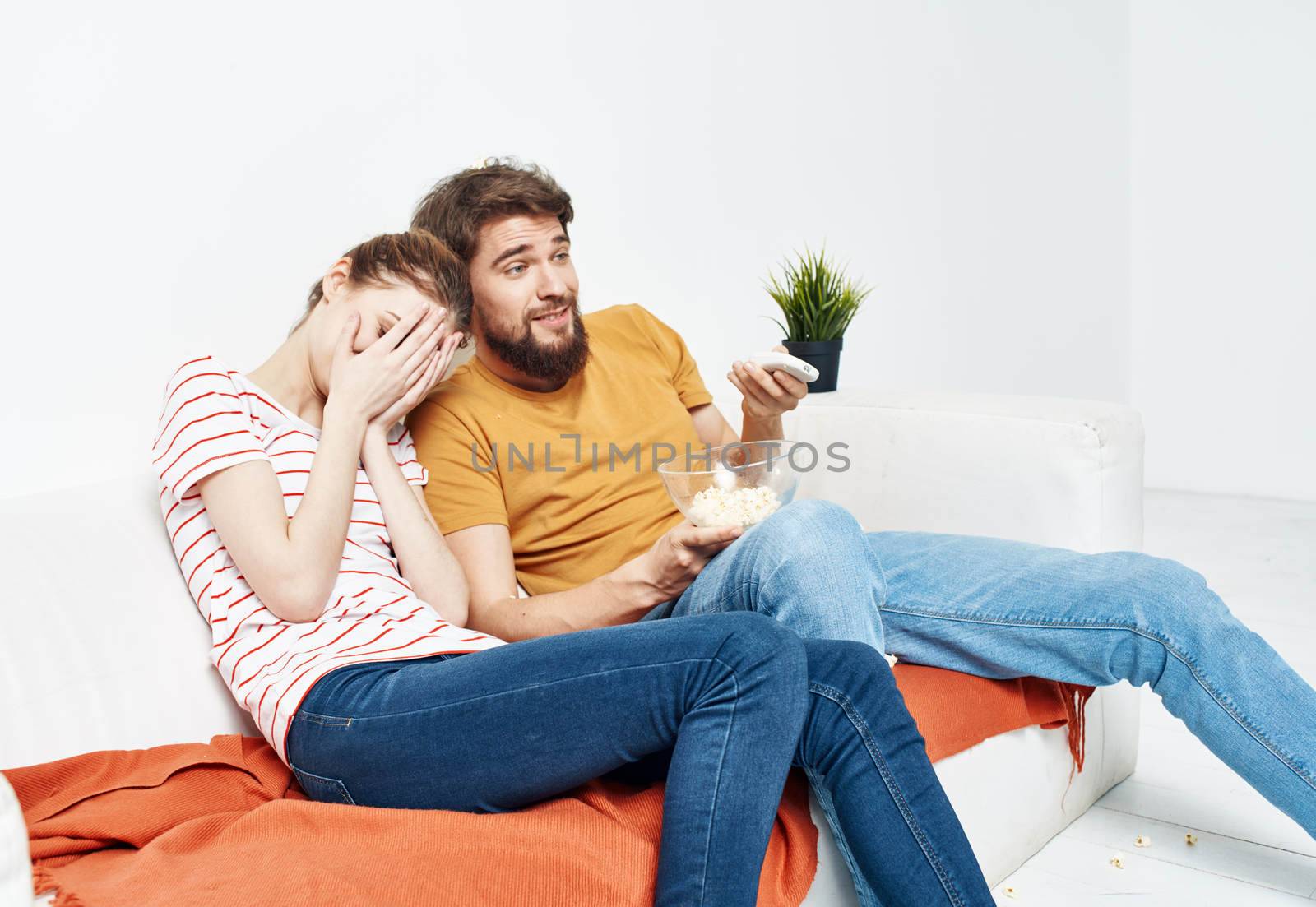 Man and woman watching movies indoors with popcorn and flower in a pot. High quality photo