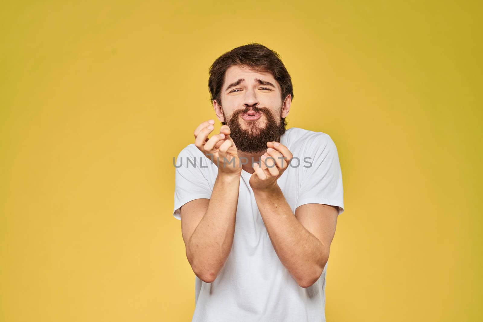 Man gesturing with hands emotions lifestyle white t-shirt yellow isolated background. High quality photo