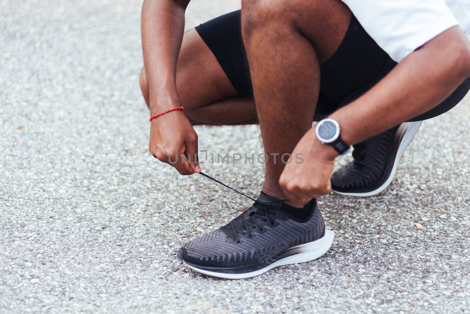 Close up Asian sport runner black man wear watch sitting he trying shoelace running shoes getting ready for jogging and run at the outdoor street health park, healthy exercise workout concept